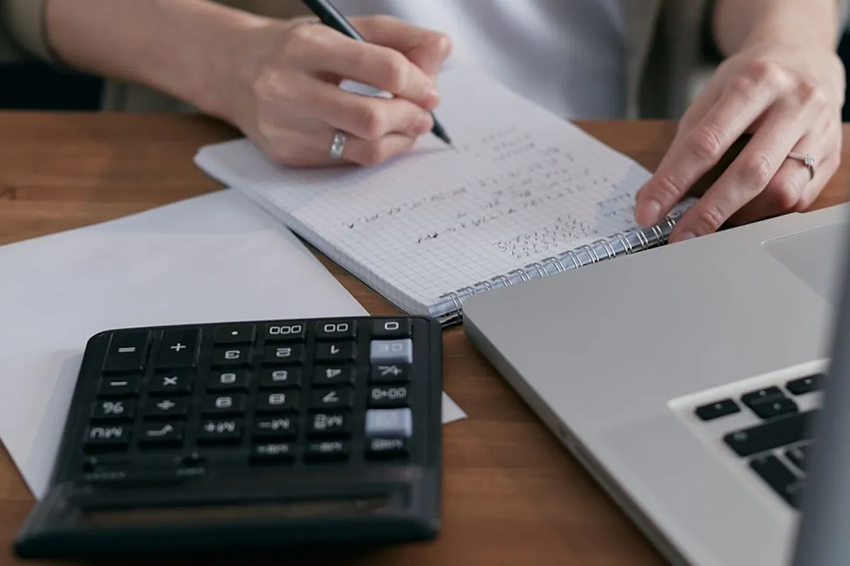 Pessoa planejando gastos com calculadora e caderno